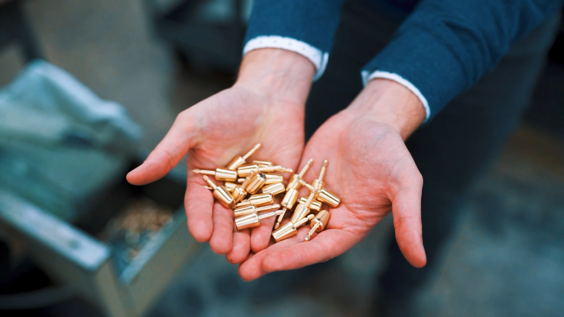 Several small metal machined components in the hands of an A-dec employee
